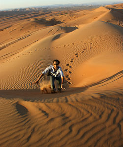 Portrait of happy man walking on sand dune