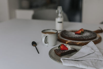 Freshly baked chocolate cake with strawberries and cream on table