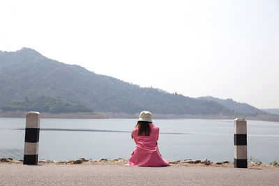 Rear view of woman looking at sea against mountains