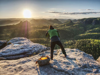 Rear view of man standing on mountain against sky