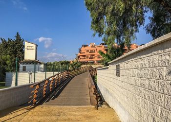 Footbridge amidst buildings against sky