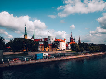 Buildings by river against sky