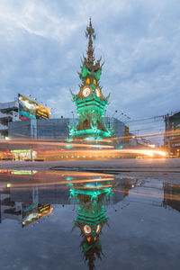 Illuminated building in city against cloudy sky