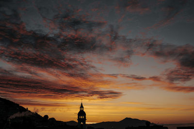 Silhouette of building against dramatic sky during sunset