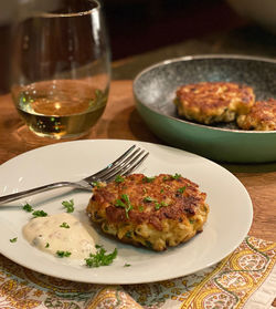 Close-up of crab cakes on plate on table with wine