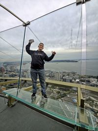 Full length of man with arms raised against sky