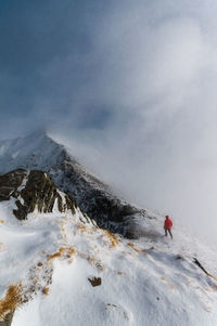 Person on snowcapped mountain against sky