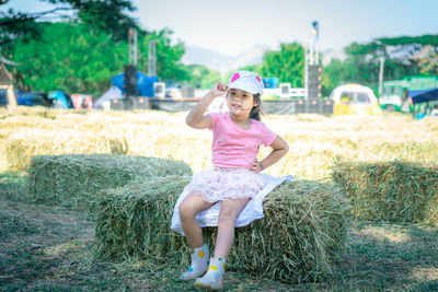Portrait of cute girl wearing cap sitting on hay bale
