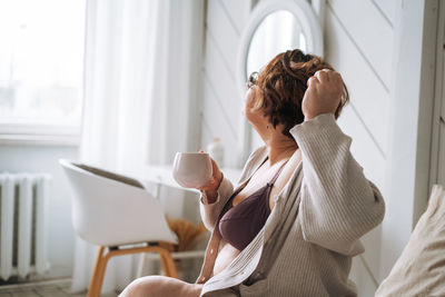 Side view of young woman using mobile phone while sitting at home