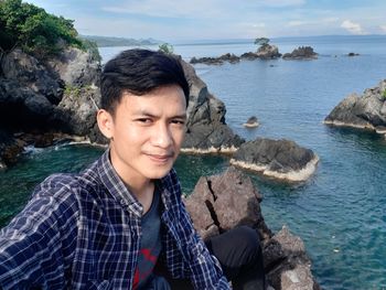 Portrait of young man looking at sea shore