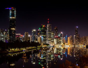 Illuminated modern buildings in city against sky at night