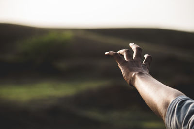 Close-up of person gesturing against sky