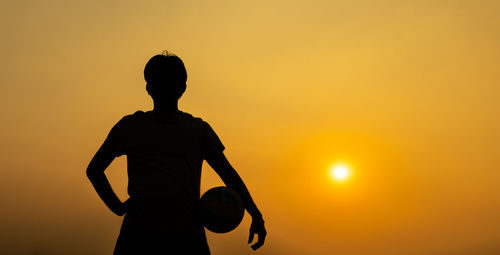 Silhouette man standing against orange sky