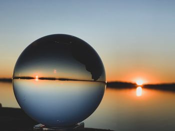 Close-up of crystal ball against sky during sunset