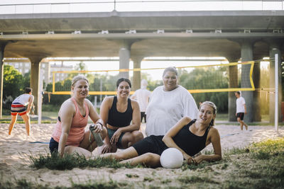 Portrait of multiracial female friends at volleyball ground