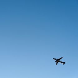 Low angle view of airplane flying in clear blue sky