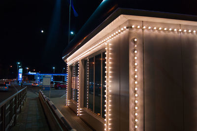 Illuminated street amidst buildings in city at night