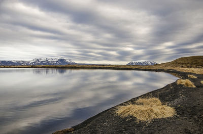 View from a beach with black sand and gravel across a reflecting lake in the myvatn area in iceland 