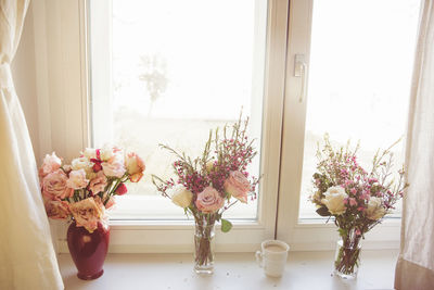 Flower vase on table against window at home