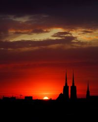 Silhouette of buildings against dramatic sky during sunset