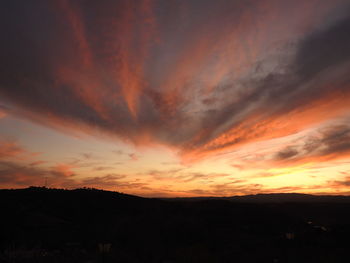 Scenic view of silhouette landscape against dramatic sky during sunset