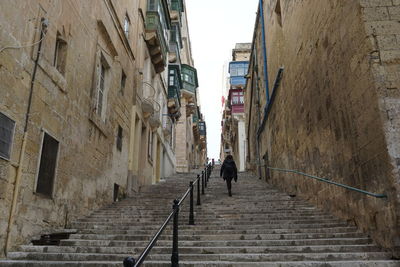 Rear view of people walking on staircase amidst buildings