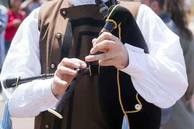 Midsection of man playing bagpipe against crowd during event