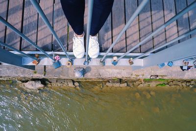 Low section of woman standing above the river