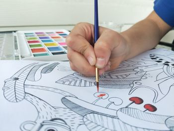 Midsection of woman holding paper with toy on table