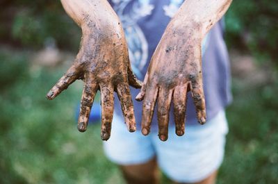 Midsection of woman showing muddy hands 