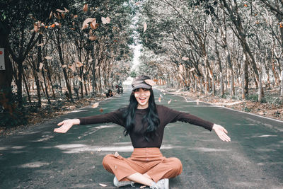 Portrait of young woman standing by tree trunk in forest