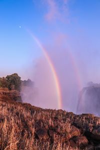 Scenic view of rainbow over landscape against sky