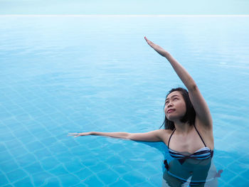 Young woman in bikini standing by swimming pool