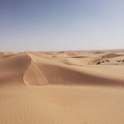 Sand dunes in desert against clear sky