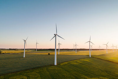 Wind turbines on agricultural land against clear sky