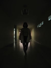 Full length rear view of man standing in illuminated building