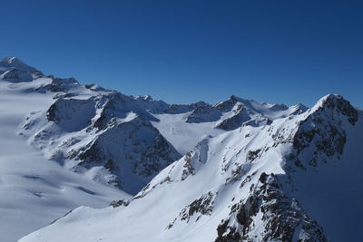 Scenic view of snowcapped mountains against clear blue sky