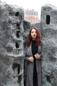 Portrait of beautiful young woman standing against wall