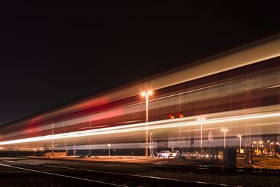 Light trails on road against sky at night