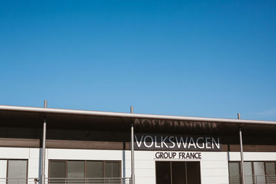 Low angle view of text on building against clear blue sky