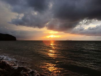 Scenic view of sea against cloudy sky at sunset