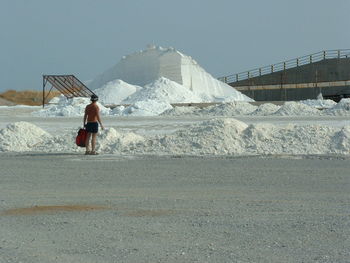 Rear view of shirtless man standing at salt mine against clear sky