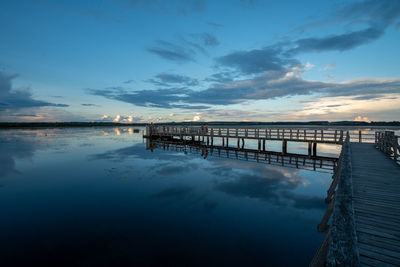 Pier over sea against sky at sunset