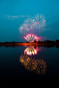 Firework display over lake against sky at night