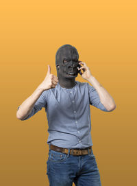 Full length portrait of young man standing against orange background