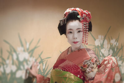 Portrait of young woman standing by flowering plants