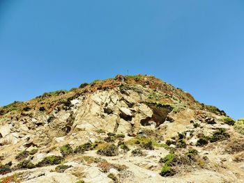 Low angle view of rock against clear blue sky