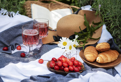 Picnic outdoors in lavender fields. rose wine in a glass, cherries and straw hat on blanket