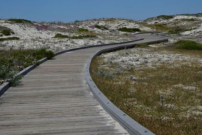 A wooden boardwalk leads over the sand dunes to the horizon and eventually the ocean.