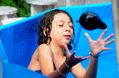 Girl catching water balloon in wading pool